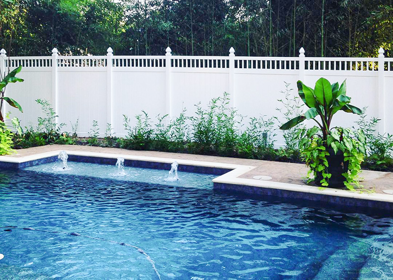 pool-fence-4 A privacy fence is surrounding a swimming pool with many plants inside.