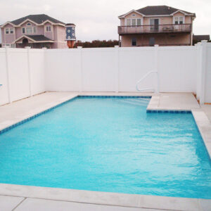A large privacy fence surrounds a swimming pool.