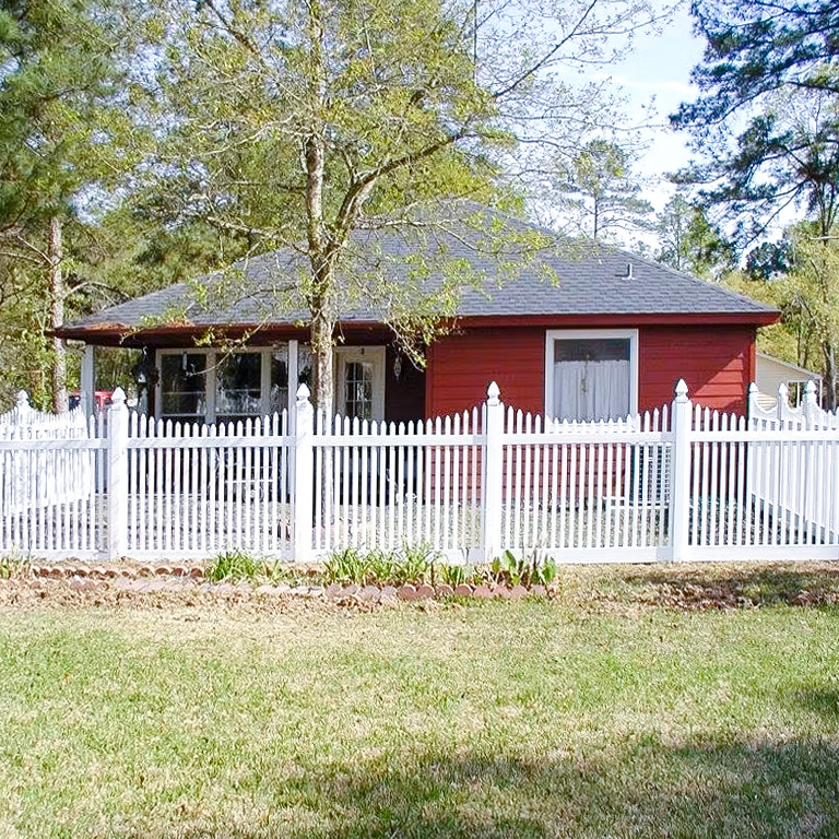 scalloped-picket-fence A scalloped picket fence surrounding a red home.